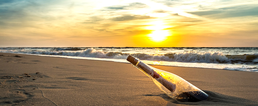 Message in a bottle on a beach against the setting sun